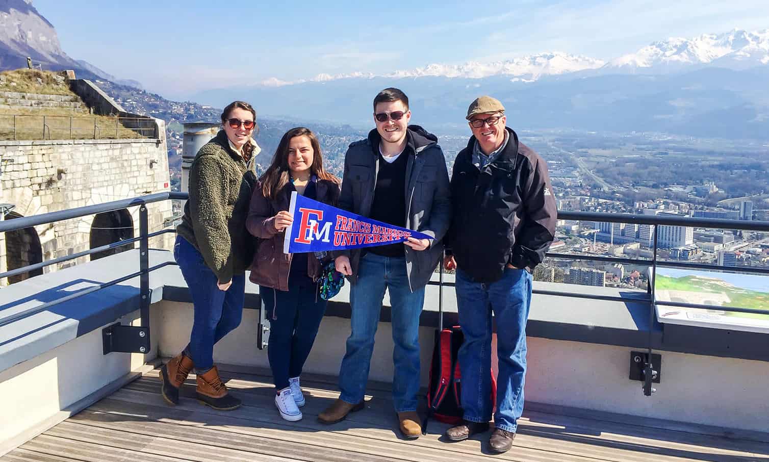 Students travelling abroad hold an FMU flag.