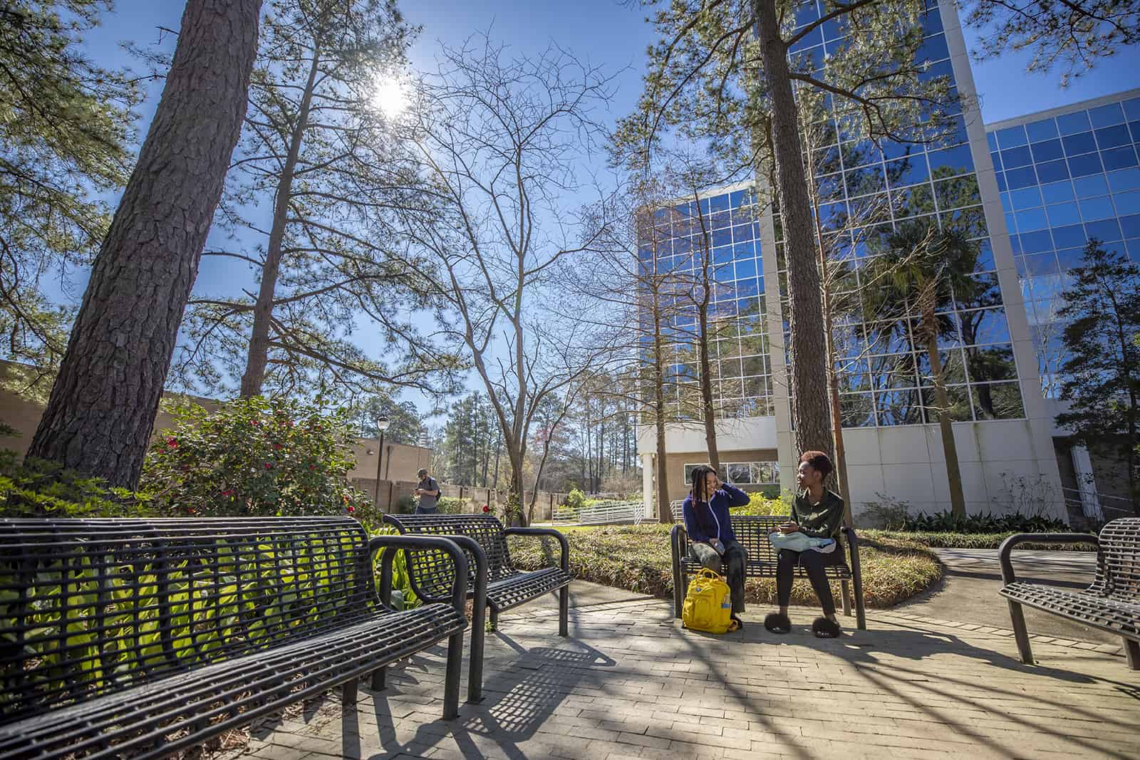 Students sit on a bench in front of Leatherman Science Facility.