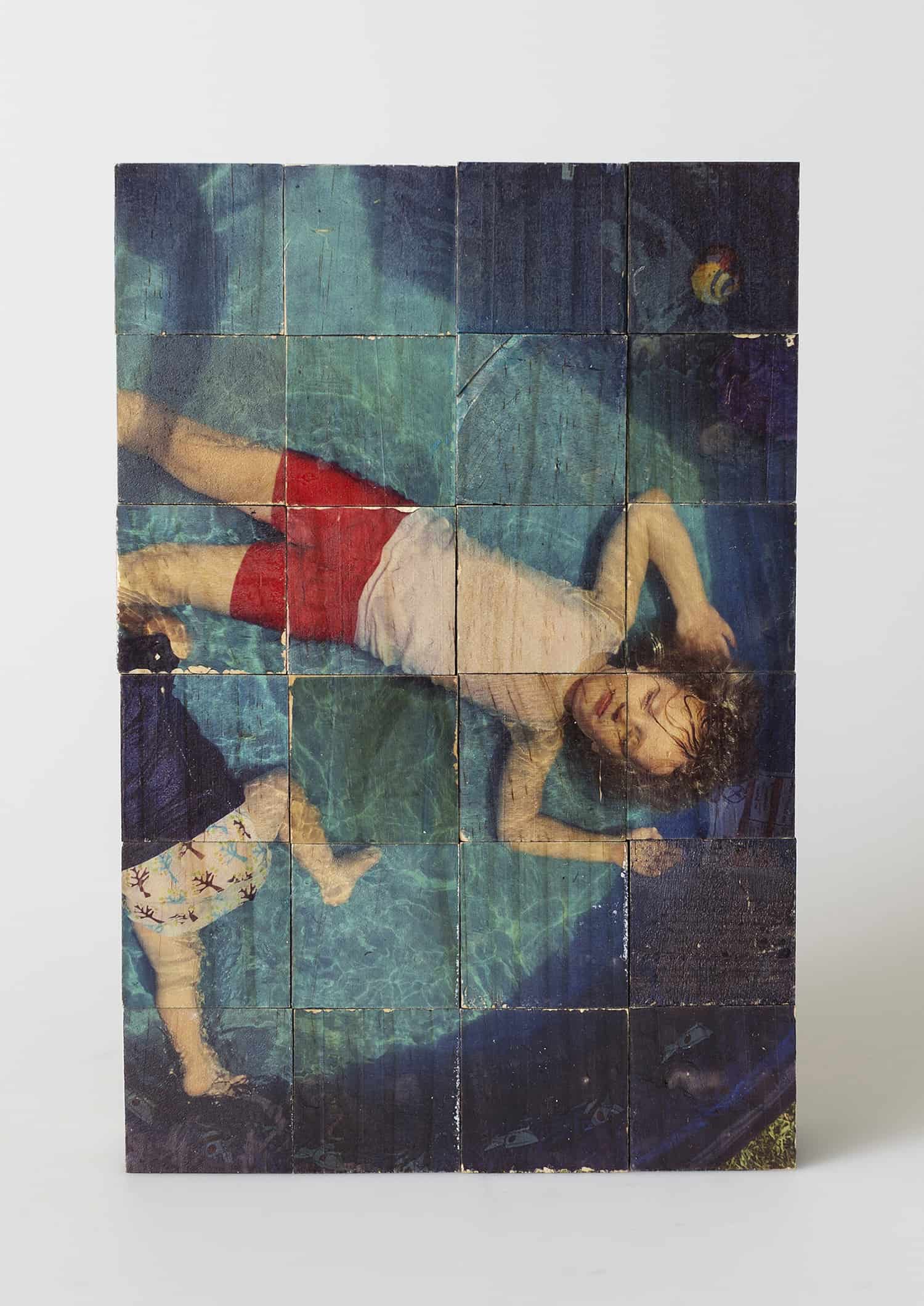 An image on wood piece depicting children resting in a pool.